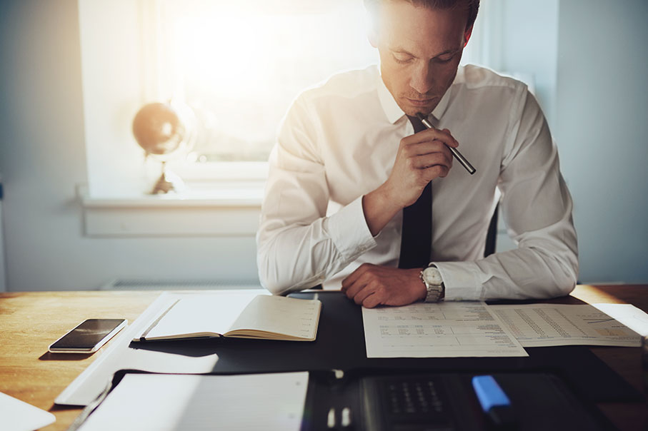 Business Man Reviewing Paper Work For An Energy Performance Certificate